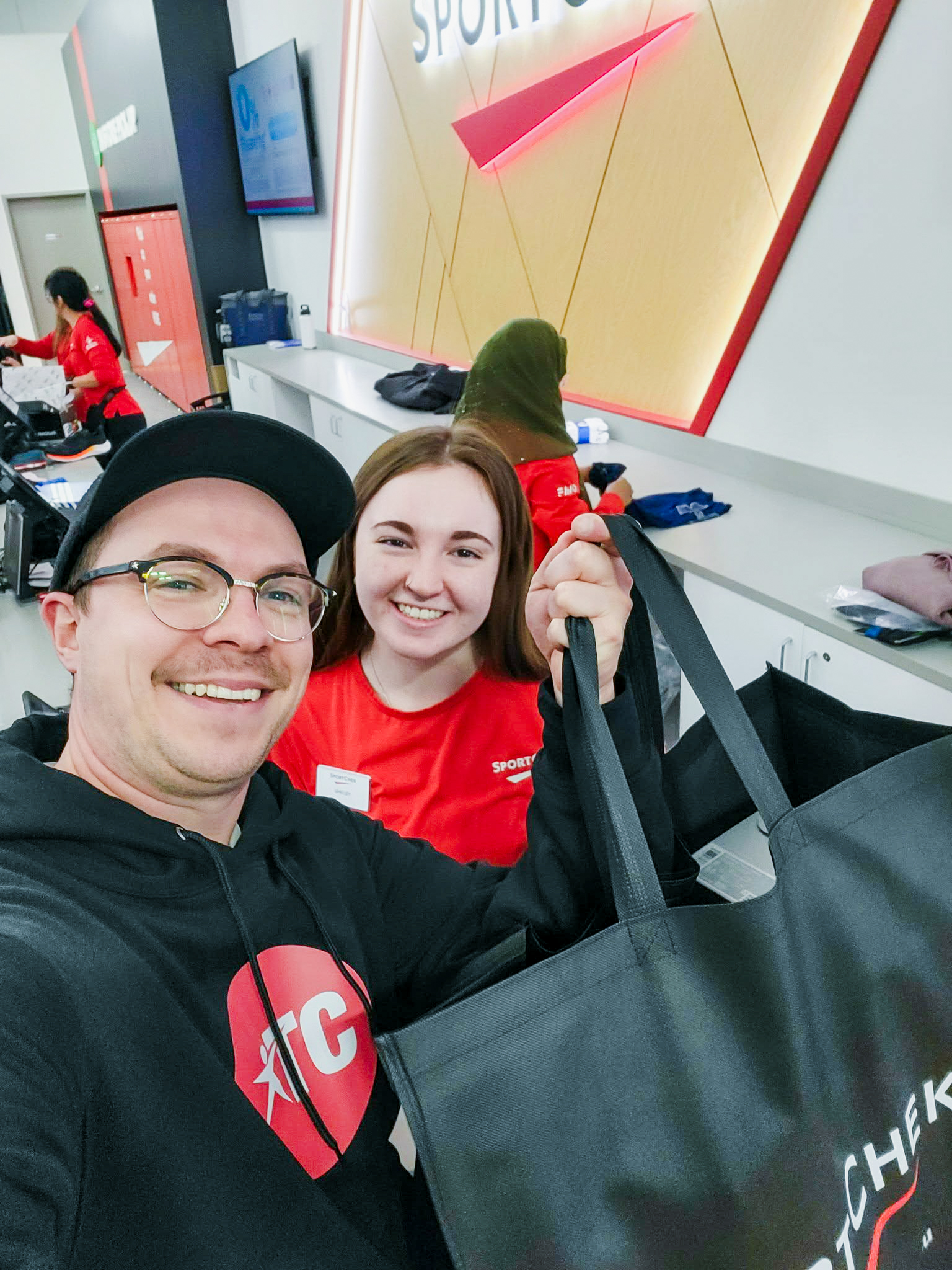 Two people smiling with Sport Check shopping bag in hand