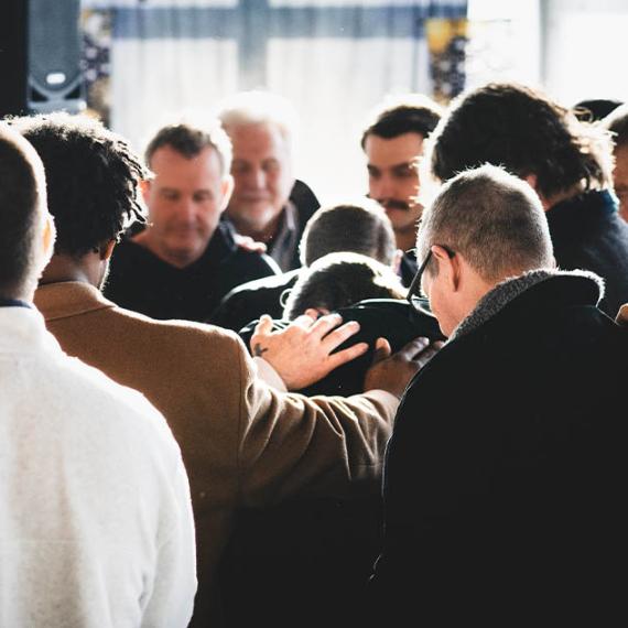 Men praying for graduate