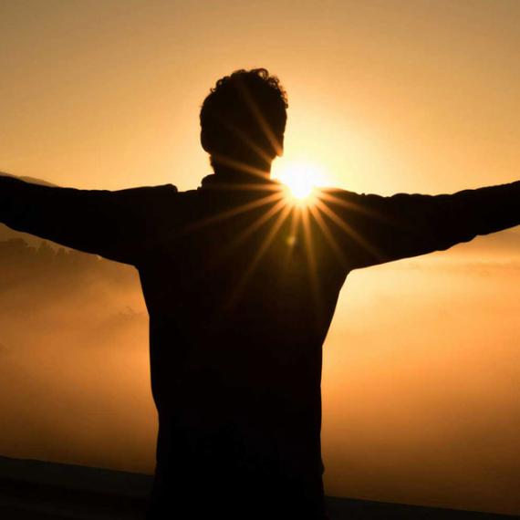 Man with outstretched arms at sunset
