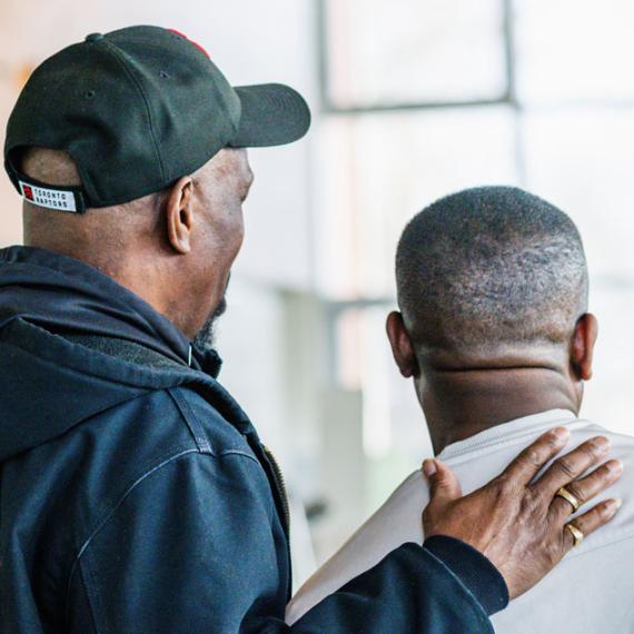 Two men, one with his arm around the other